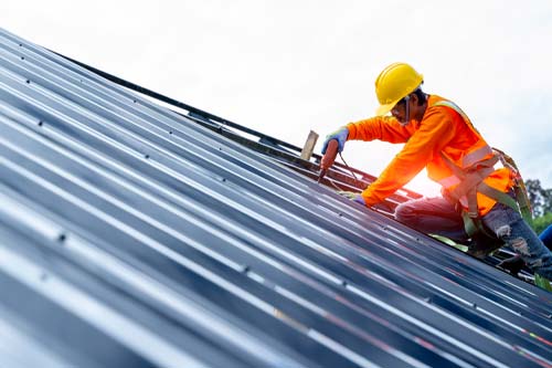 Contractor working on roof during sunrise